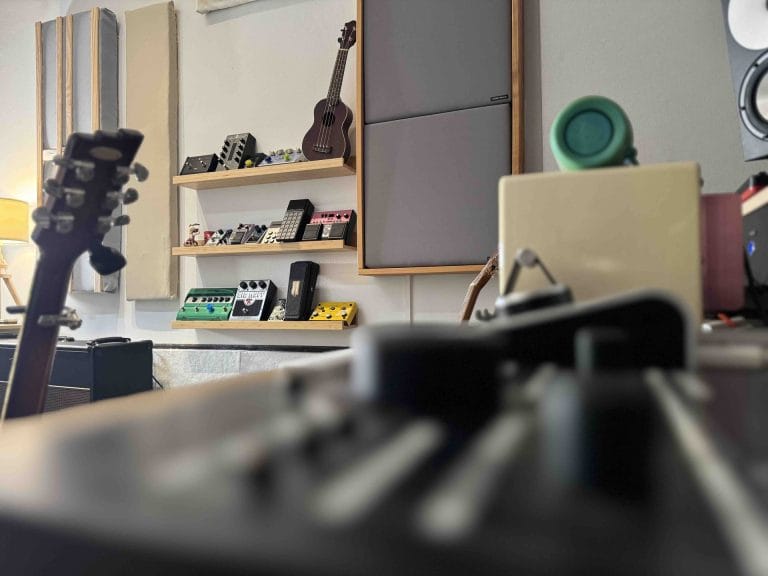 Mesa de control con guitarra, ukelele y estanterías del estudio