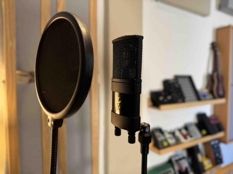 Micrófono de condensador con filtro antipop y pedales de guitarra al fondo
